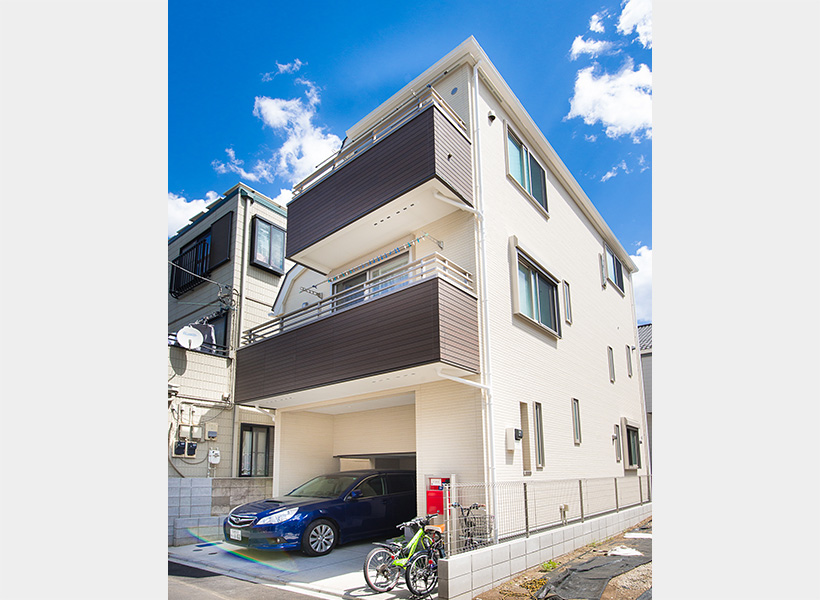 アイボリーを基調に、バルコニーの木目調のブラウンが落ち着いた雰囲気を演出。シンプルな外観に赤いポストがアクセントになっています。